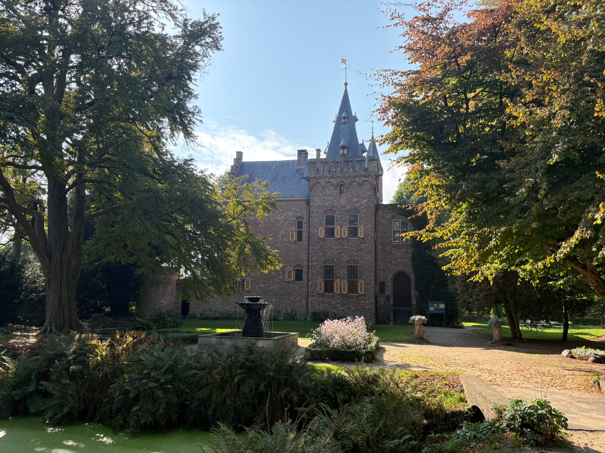 Hof Sypesteyn tussen de bomen, met fontein en roze bloemen